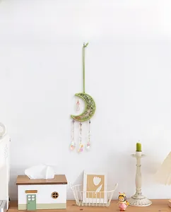 Detailed shot of brass moon suncatcher with green woven frame and crystal prism pendants