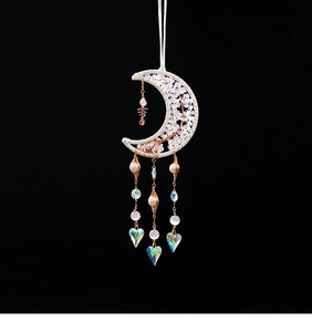 Macro view of crystal moon suncatcher with rainbow heart prisms and beaded tassels