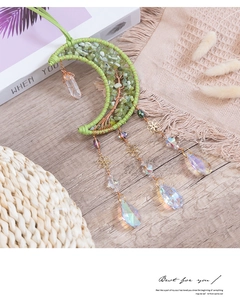Detail view of handmade brass moon suncatcher with green crystal stones and tree of life