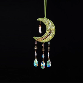Macro detail of brass moon suncatcher with green crystal life tree and prism drops