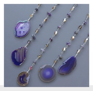 Detail of purple agate slice wall hangings with metallic chains and crystal beads