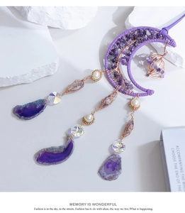 Dettaglio dell'acchiappasogni a mezzaluna con cristalli viola, perle e fette di agata