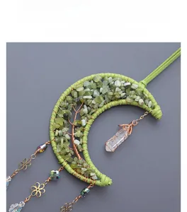 Detail of moon-shaped suncatcher with green crystal life tree and quartz crystal point