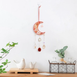 Moon-shaped crystal dreamcatcher with orange stones and red agate slice on white wall