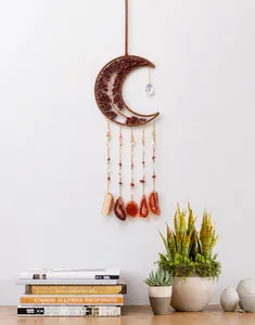 Handmade crescent moon dream catcher with red crystal chips and agate slices on white wall