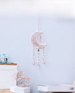 Dettaglio decorazione da parete a luna con quarzo rosa e albero della vita in metallo