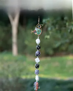 Detail of handcrafted tree of life ornament featuring colorful crystals and woven wire bird