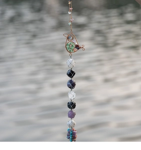 Close-up of bird-shaped copper wire frame with colorful natural crystal stones