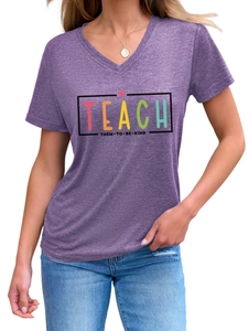 Détail du t-shirt violet col V avec inscription Teach Them To Be Kind imprimée dessus