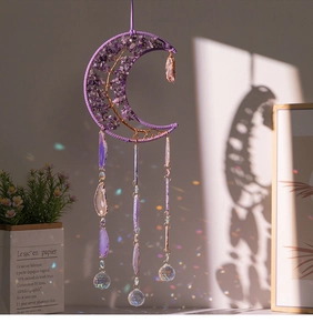 Detail of purple moon suncatcher with tree of life and agate slice casting rainbow light