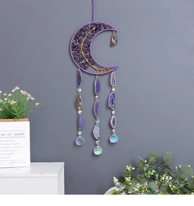 Purple crystal moon suncatcher with agate slices and prisms hanging on a grey wall