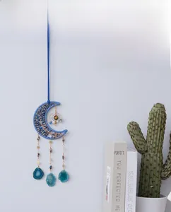 Detail of bohemian crescent moon wall hanging with blue weaving and agate slice pendants