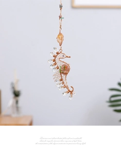 Macro shot of handmade seahorse ornament with gold wire, crystals and natural stones
