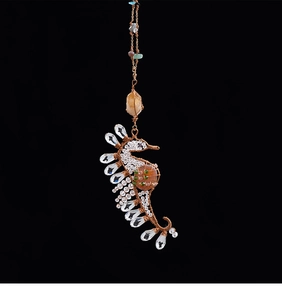 Detail of wire-wrapped seahorse pendant with clear crystals and orange stone
