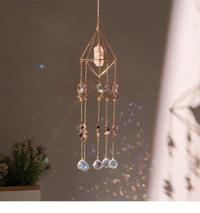 Detail view of crystal suncatcher with gold frame, pink stone, and rainbow light refraction