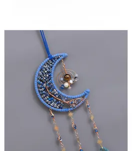 Detail of handcrafted blue crescent moon wall decor with wire-wrapped tree and hanging stars