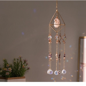 Rainbow refraction on wall from a prism suncatcher with pink crystals and moon charms