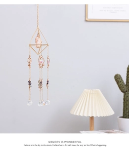 Detail of crystal suncatcher with golden frame, pink raw stone and faceted glass ball