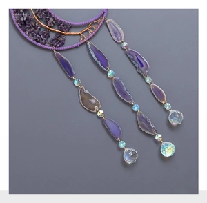 Detail view of purple agate slices and crystal ball on a moon-shaped tree of life suncatcher