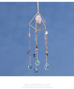 Detail of suncatcher prism with gold metal frame, raw crystals and faceted glass ball
