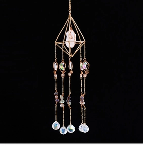 Detail of hanging suncatcher with golden geometric frame and faceted crystal ball
