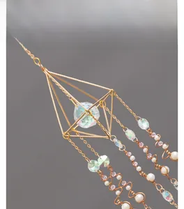 Detail of geometric gold suncatcher with colorful crystal prism and white pearls