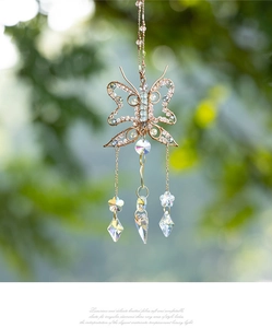 Macro detail of handmade wire-wrapped butterfly suncatcher with crystal pendants