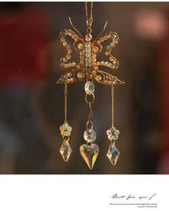 Detail of wire-wrapped golden butterfly suncatcher with crystal hearts and blue beads