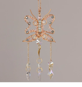 Macro detail of wire-wrapped butterfly suncatcher with rose gold wire and crystal pendants