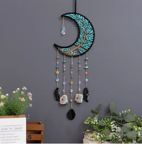 Detail of moon suncatcher with tree of life and turquoise stones on gray wall