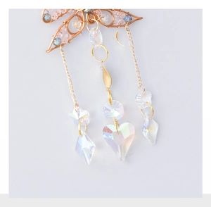 Macro detail of wire-wrapped heart suncatcher with iridescent crystals and gold frame