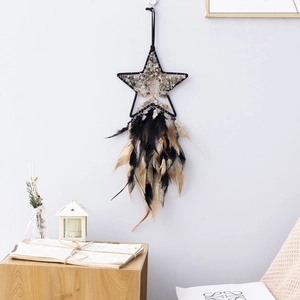 Star-shaped Tree of Life dream catcher with green crystals and feathers on white wall