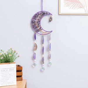 Purple amethyst moon suncatcher with agate slices and crystal balls on a white wall