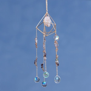 Golden suncatcher ornament with rose quartz stone and crystal ball on blue background