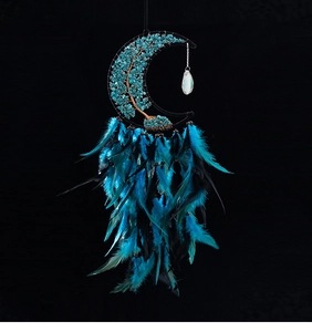 Detail of teal crystal tree of life inside a crescent moon dreamcatcher with feathers