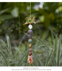 Detail of handmade wire-wrapped bird charm with seven chakra raw gemstones