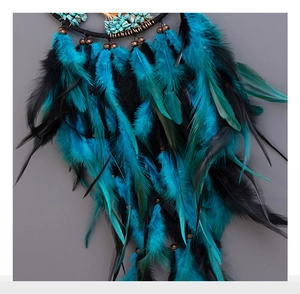 Detailed shot of peacock blue feathers and turquoise stones on a dreamcatcher charm