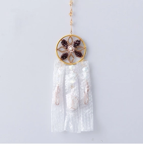 Detail of bohemian dream catcher with gold metal frame, red beads and white fabric tassels