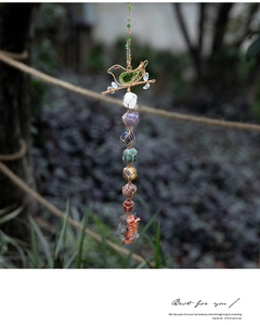 Detail of a bird-shaped wire crystal pendant featuring seven natural chakra healing stones