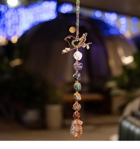 Macro detail of wire-wrapped metal bird ornament with colorful raw seven chakra stones