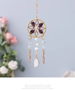 Detail of bohemian moon star dream catcher with raw smoky quartz crystals and golden charms