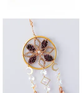 Detailed close-up of handmade golden dreamcatcher with tea crystal and celestial charms