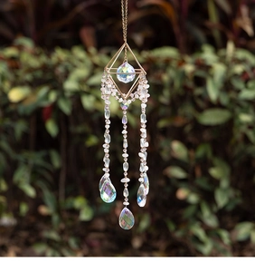 Detail of crystal suncatcher with gold geometric frame and colorful prism beads