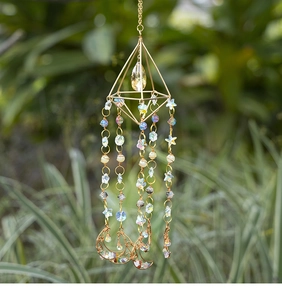 Detail of a geometric golden suncatcher with teardrop crystal and moon metal frame