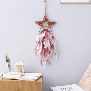 Bohemian star dream catcher with pink white feathers and crystals on a grey wall