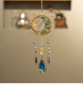 Détail d'un attrape-soleil soleil et lune avec pierres vertes et cristaux suspendus
