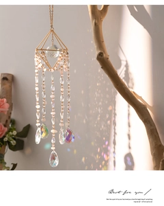 Detail of crystal suncatcher with golden geometric frame and pink beads reflecting colorful light