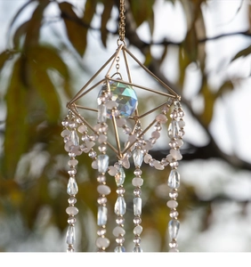 Detail of geometric gold suncatcher with multifaceted crystal ball and prismatic chains