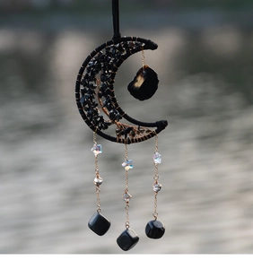 Detail of tree of life black moon suncatcher with raw crystal stones on golden chains