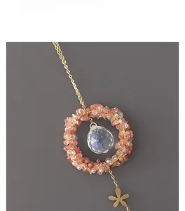 Detail view of pink crystal ring pendant with multifaceted glass ball on gold chain